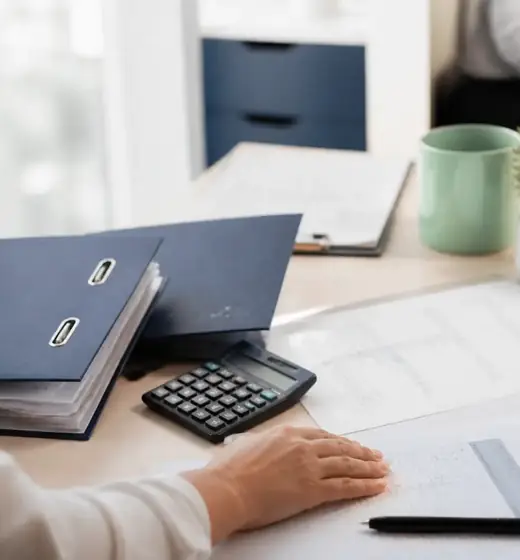 Calculatrice, classeurs indigo et relevés chiffrés sur un bureau clair