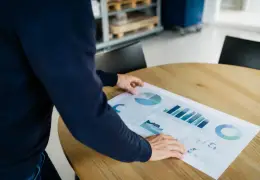Dirigeant de PME devant un tableau de bord imprimé sur une table de réunion