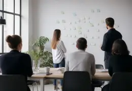 Une équipe de travail réunie autour d’une table avec des notes collées sur un mur